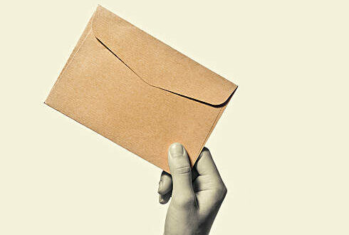 Hand with envelope from kraft paper, isolated, toned, black and white